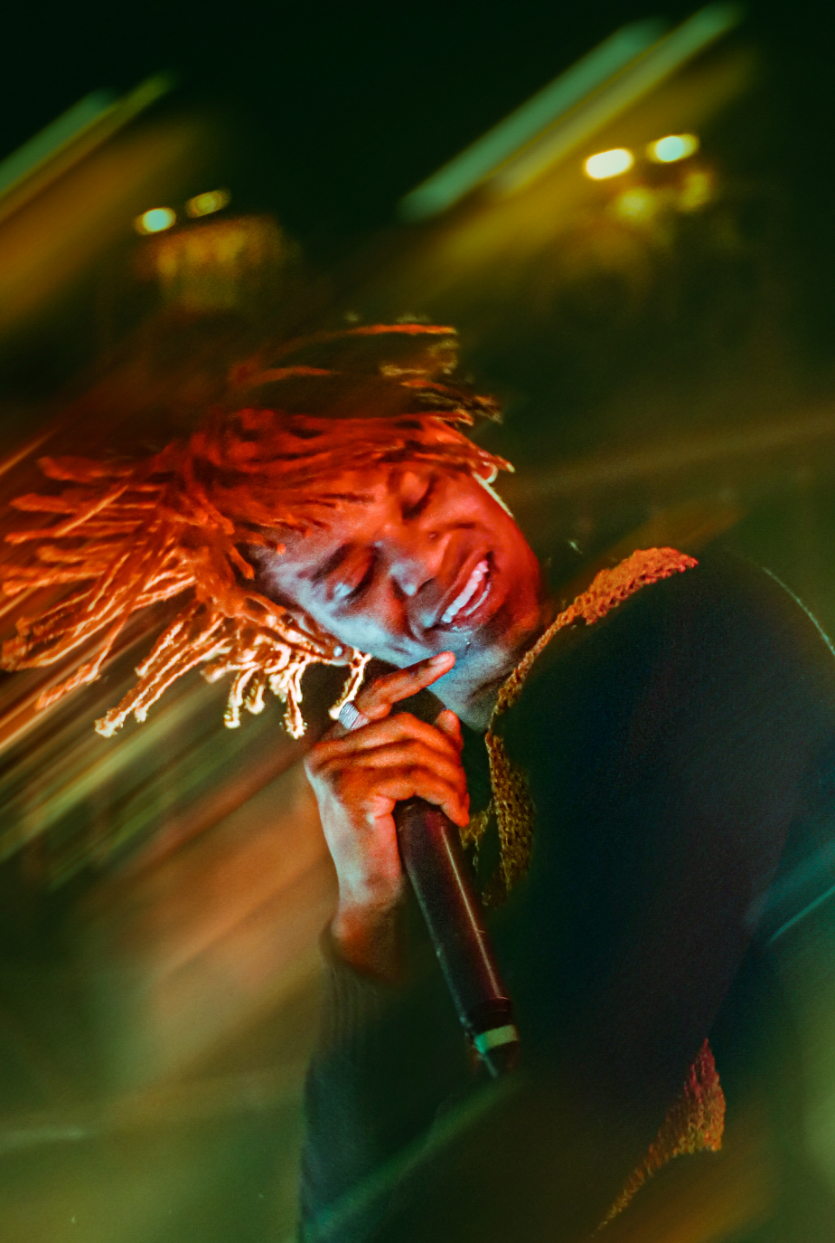 Artist with flowing red hair performing energetically on stage