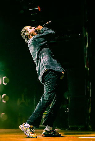 Band member performing on stage with dramatic lighting